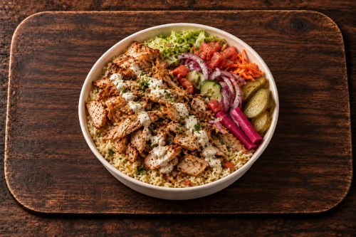 Chicken Döner rice bowl with Mediterranean accompaniments, pickles and house sauce